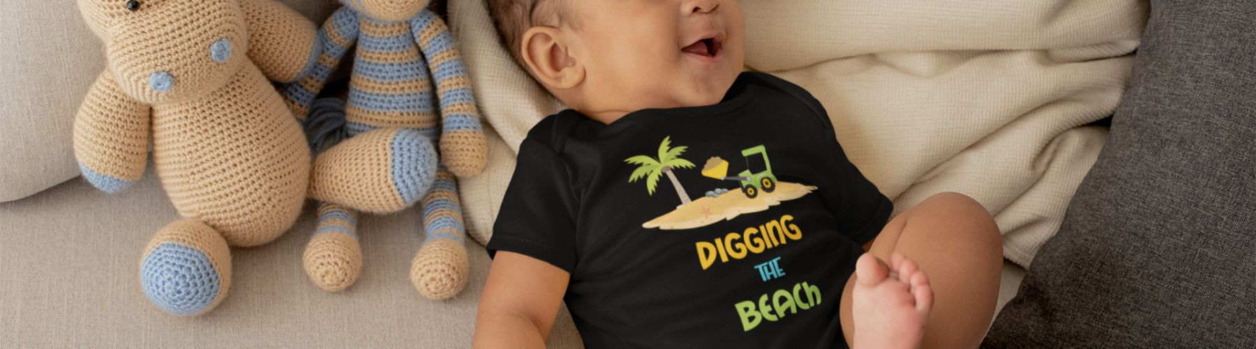 Baby Beach Clothes is an image of a onesie-type baby outfit in black with the text Digging the Beach with an image of a palm tree and sand. The baby is a boy. 